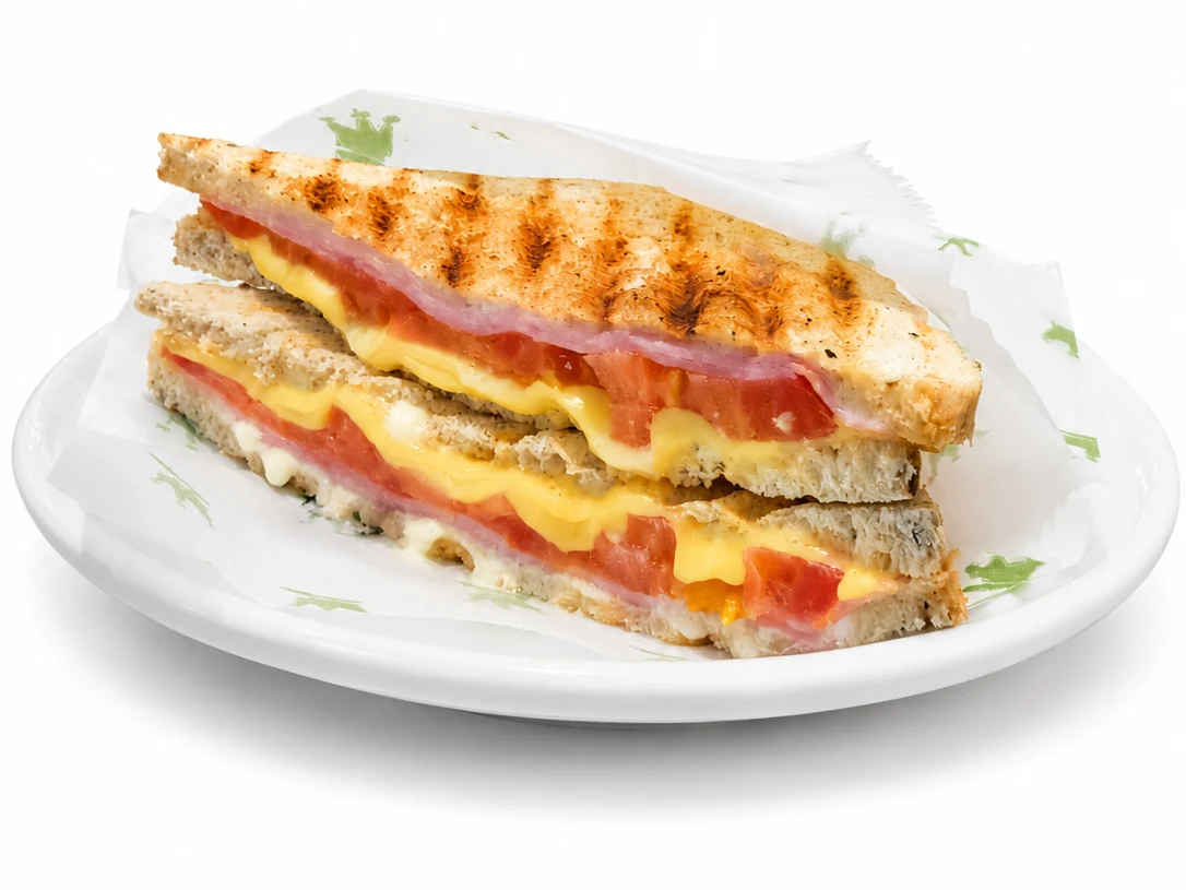 Toast Misto servido no prato, com presunto, queijo e tomate visíveis.